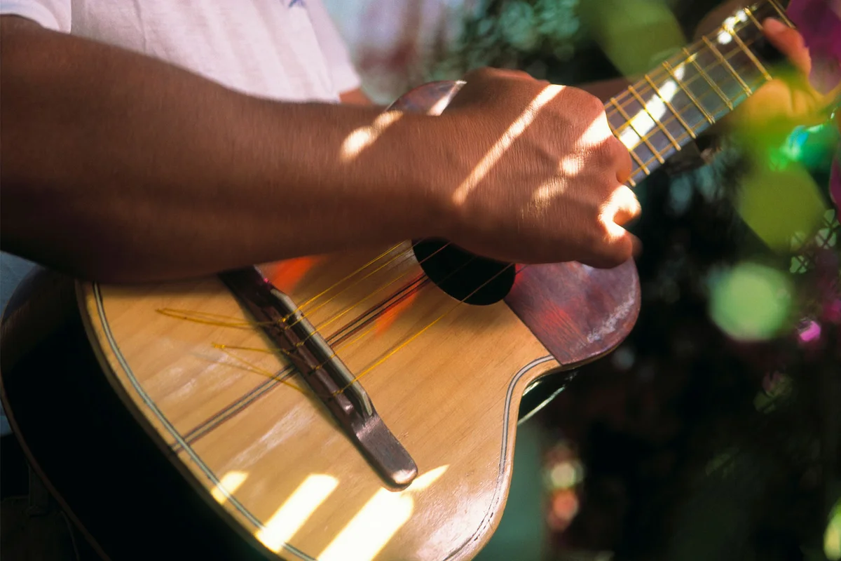 man playing cuatro four string instrument
