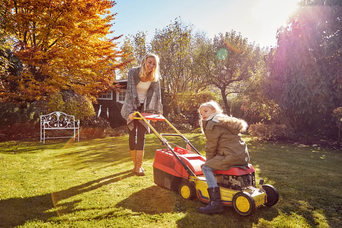 Mother with daughter in garden lawn mowing