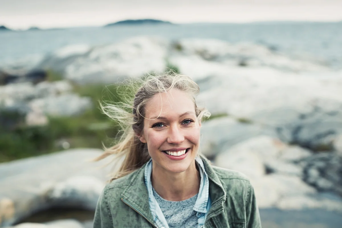 Portrait of happy young woman on rock by sea