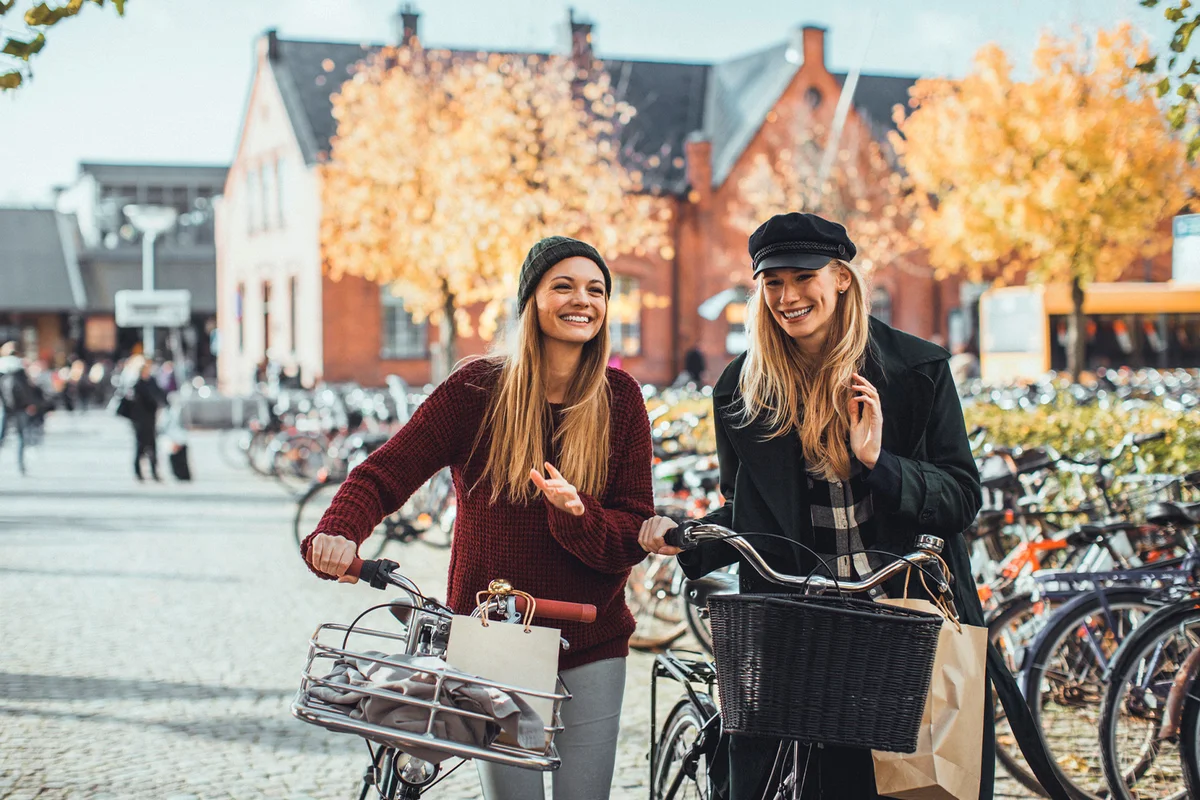 young women leading their bikes through city