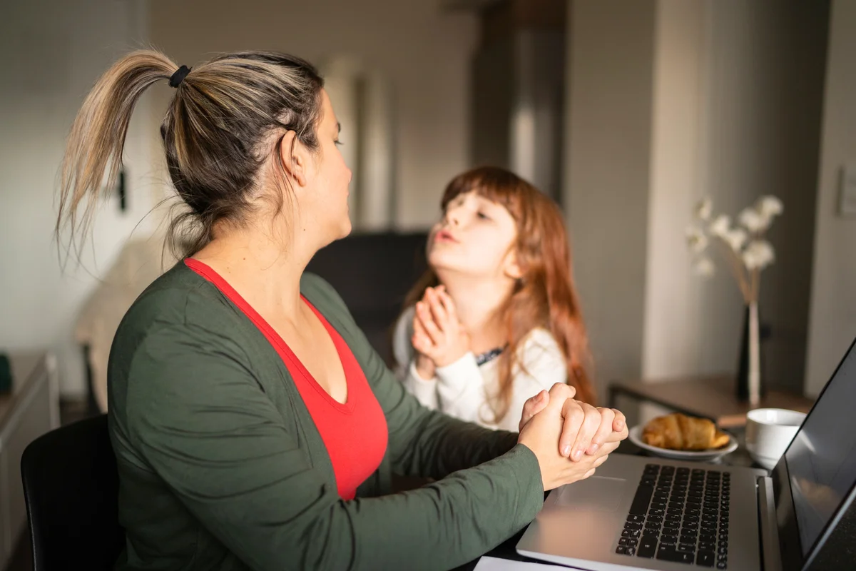 Girl asking something to her mother who's working at home