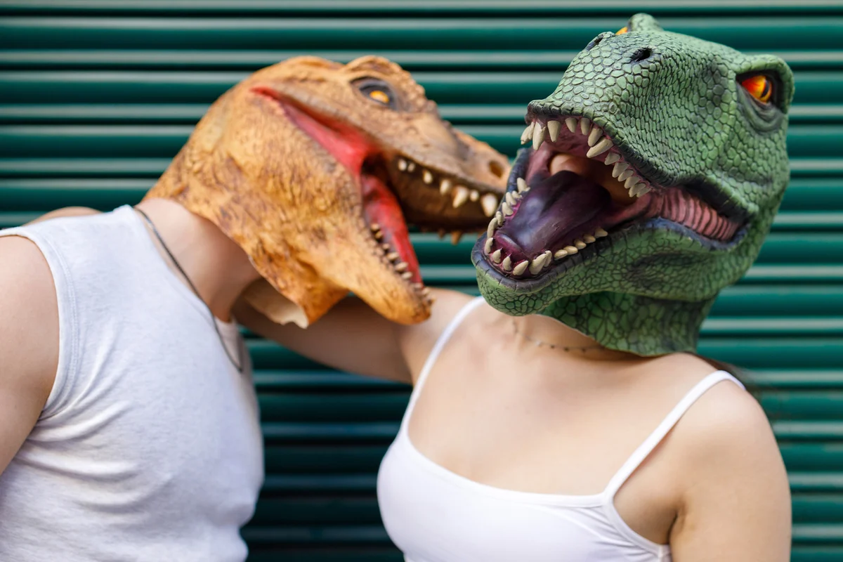 Male and female wearing dinosaur mask