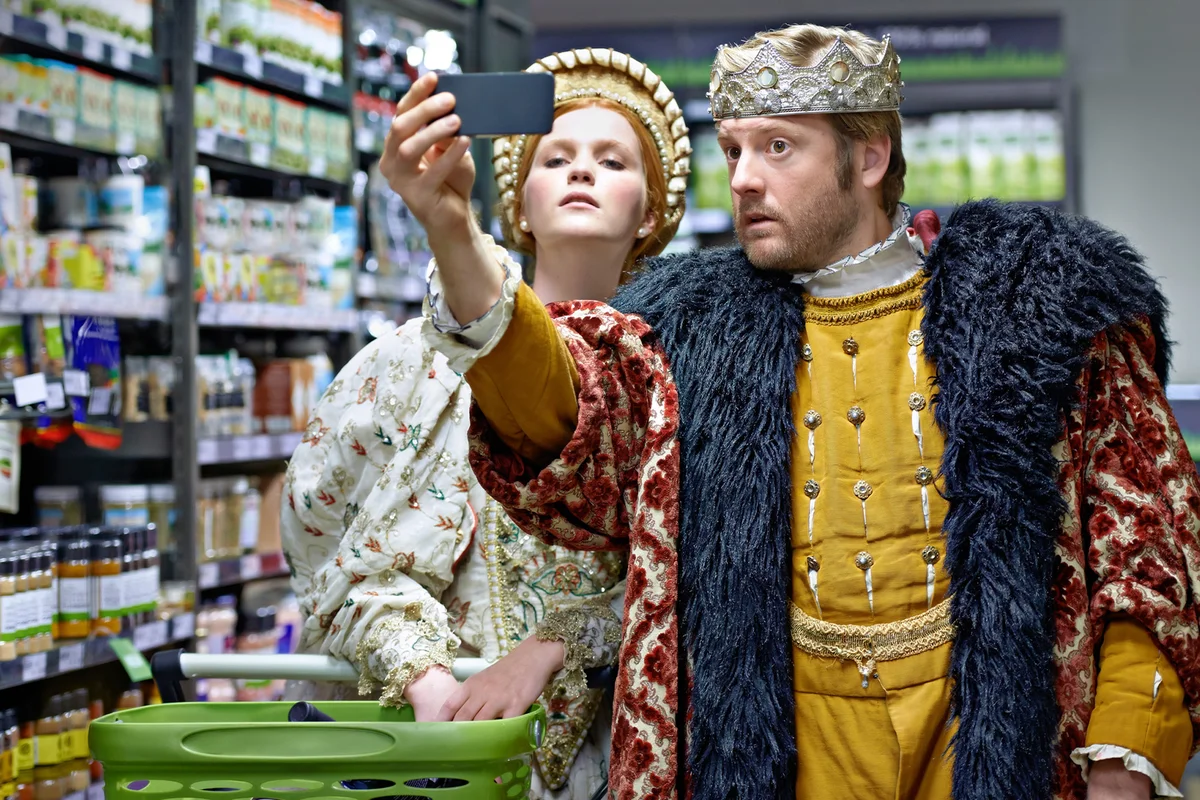A king and queen taking a selfie in their local supermarket