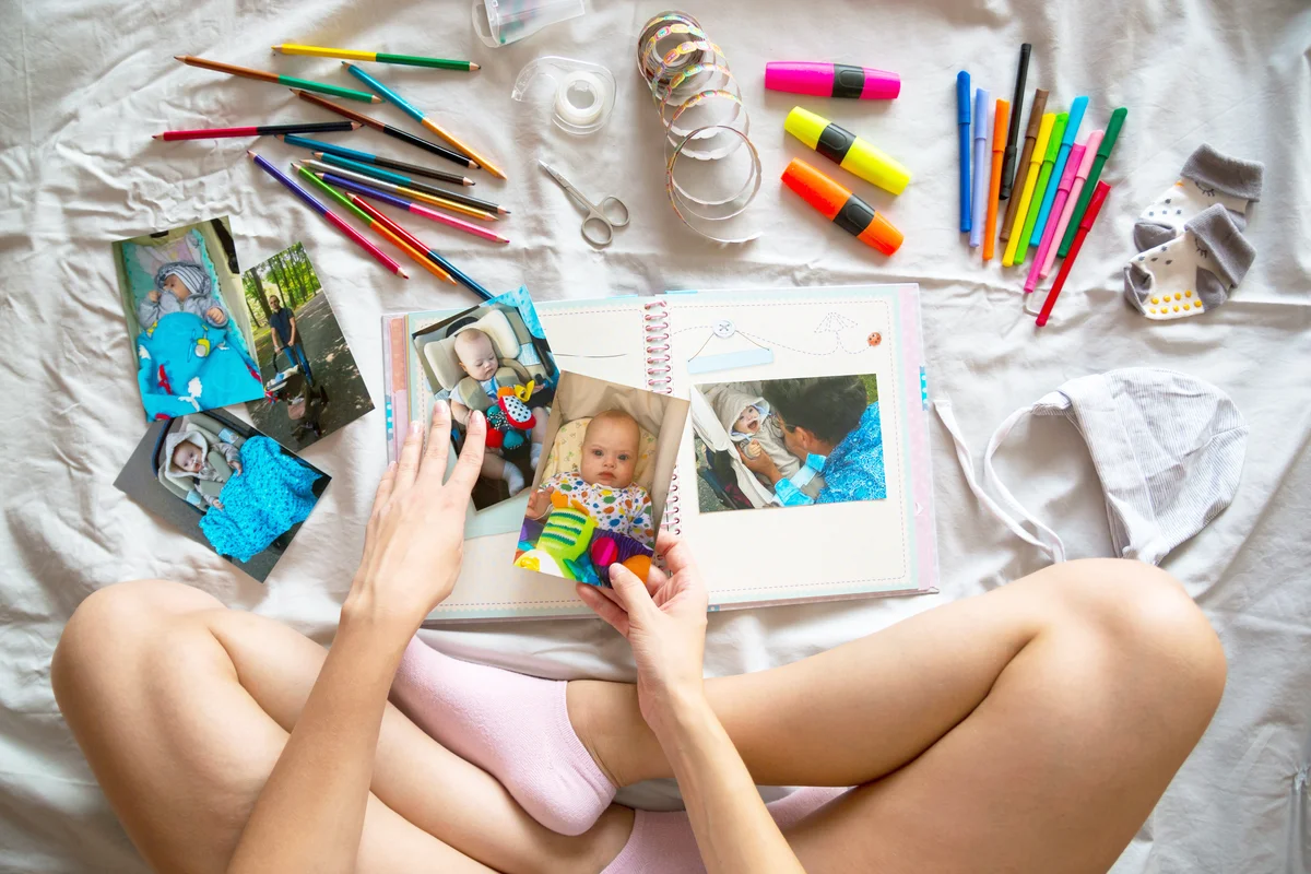 Woman Holding Photographs On Scrapbook By Equipment