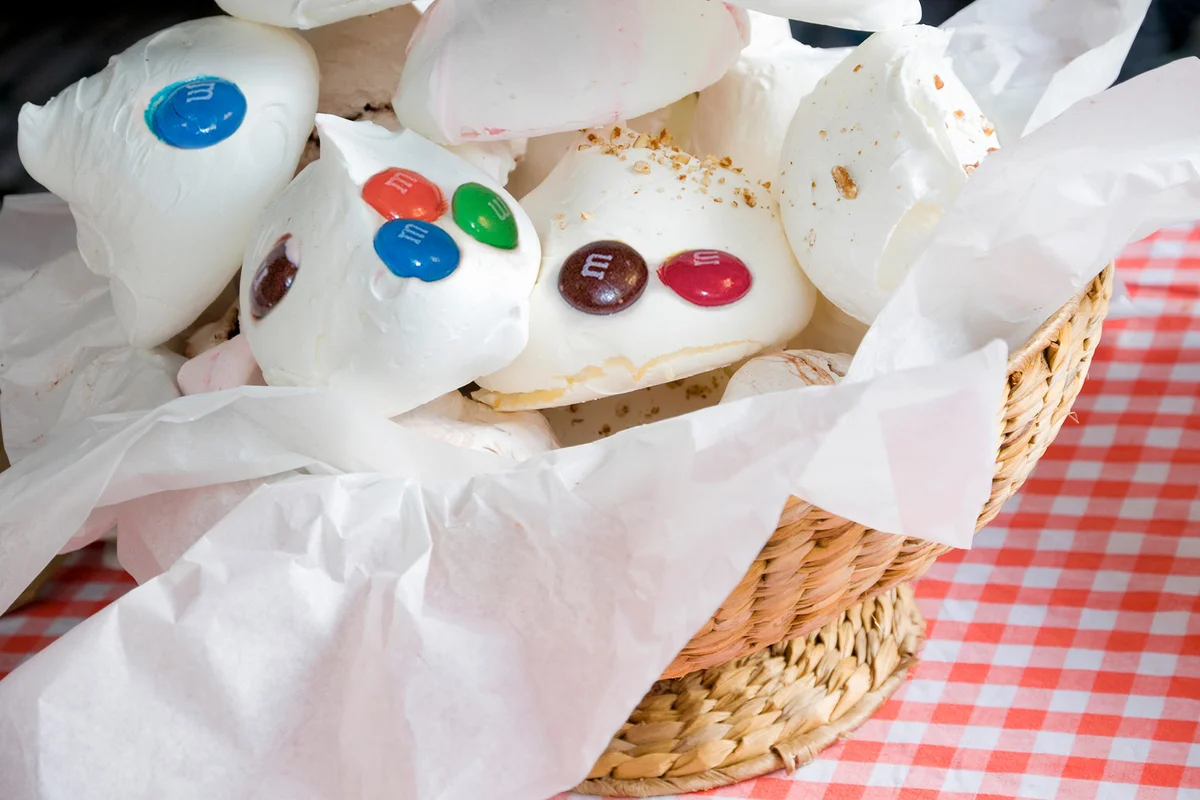 White meringues in wicker basket on red gingham kitchen table cloth
