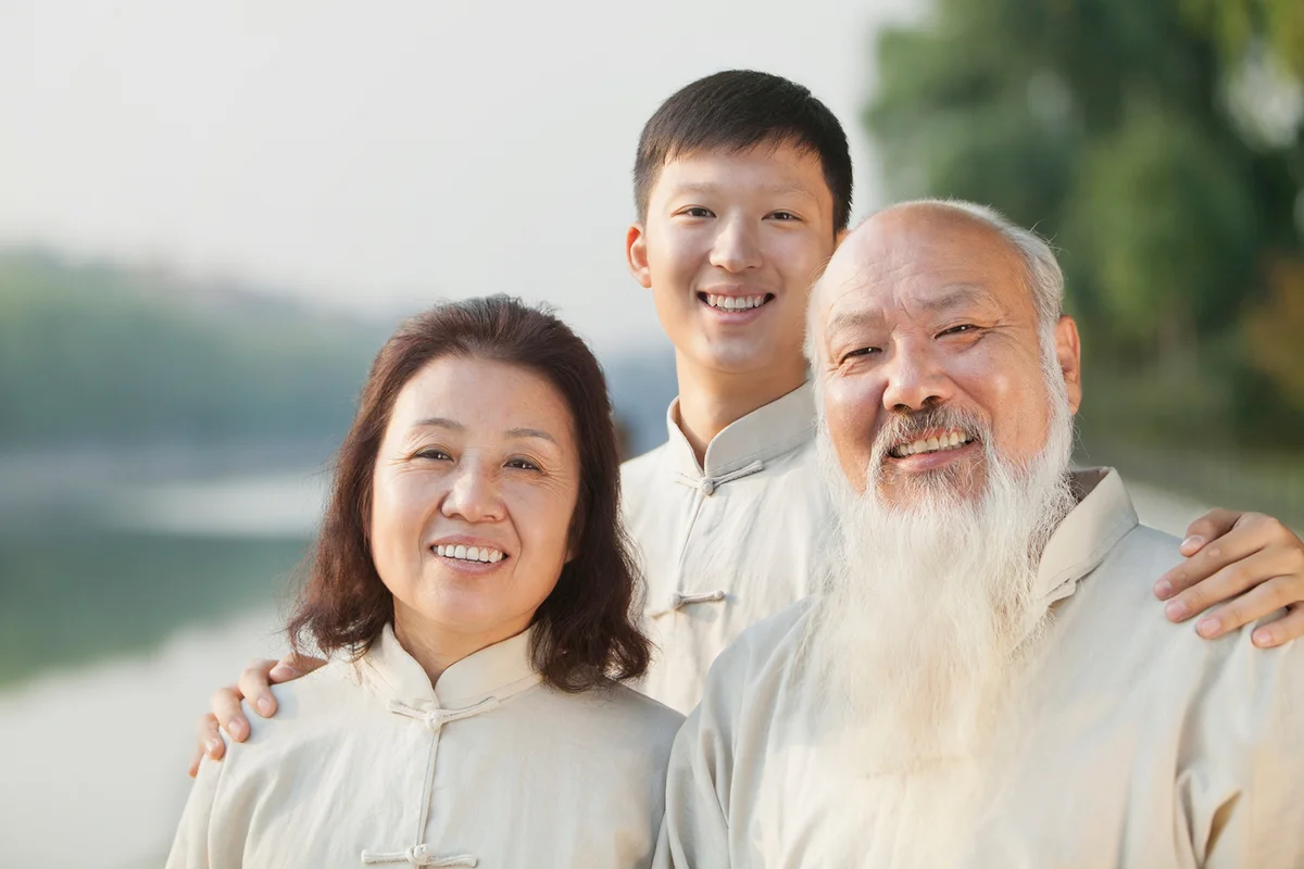 Three Chinese People With Tai Ji Clothes Smiling At Camera