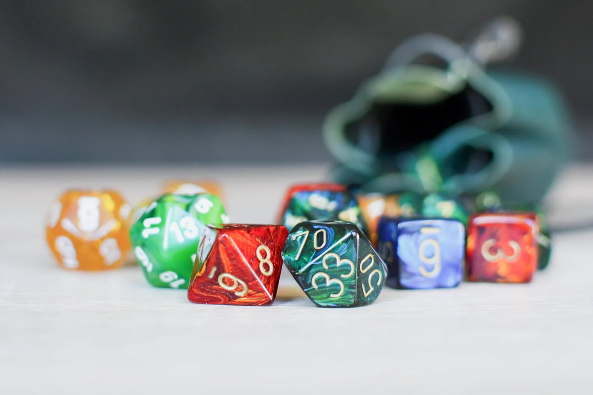 Different colorful role playing dice on table with blurry storage leather bag in backgorund