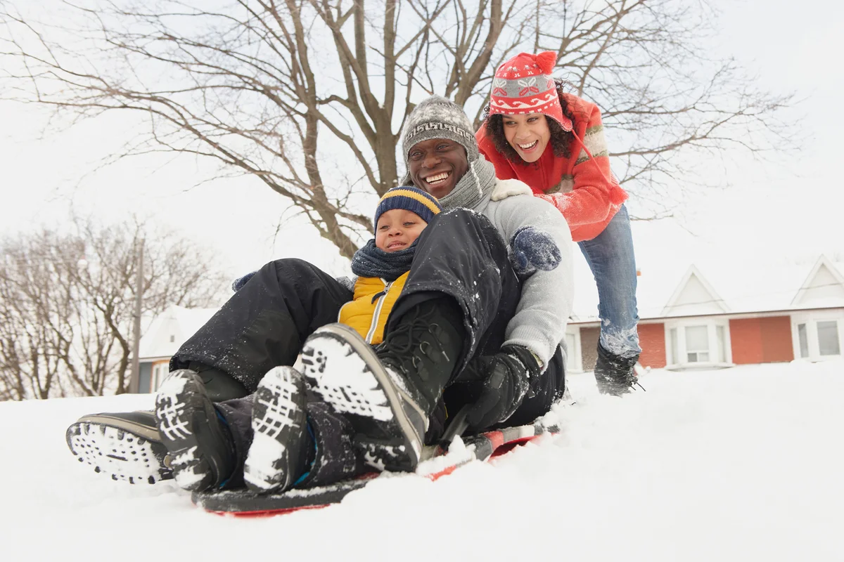 Black family sledding in snow