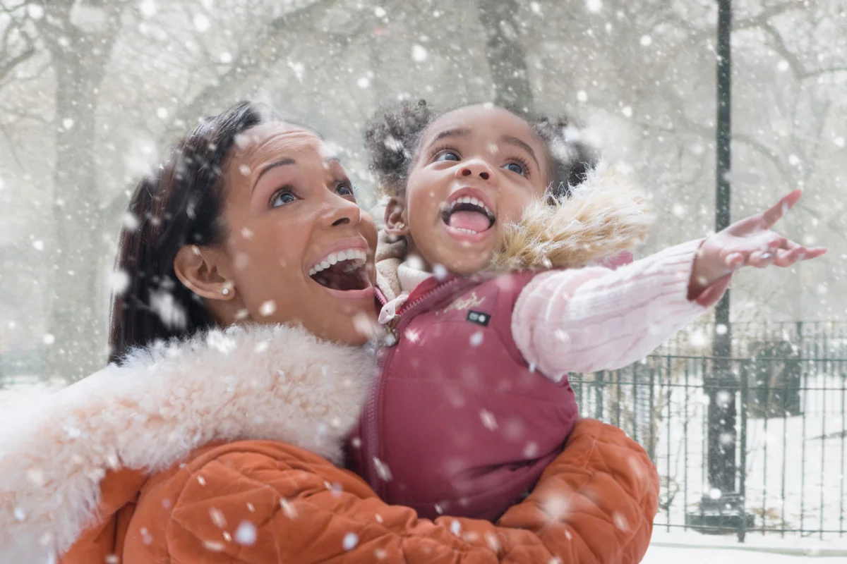 mother holding daughter in falling snow