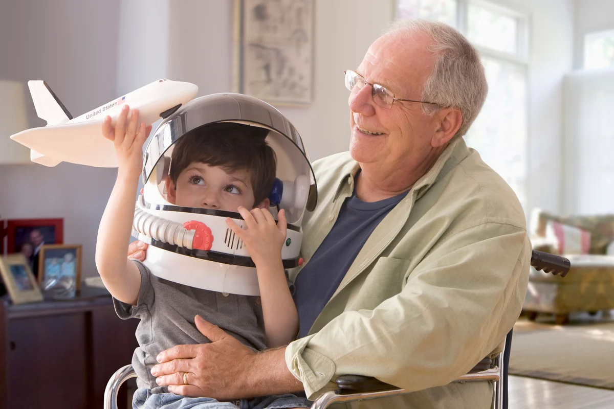 Boy in space helmet sitting on grandfather's lap