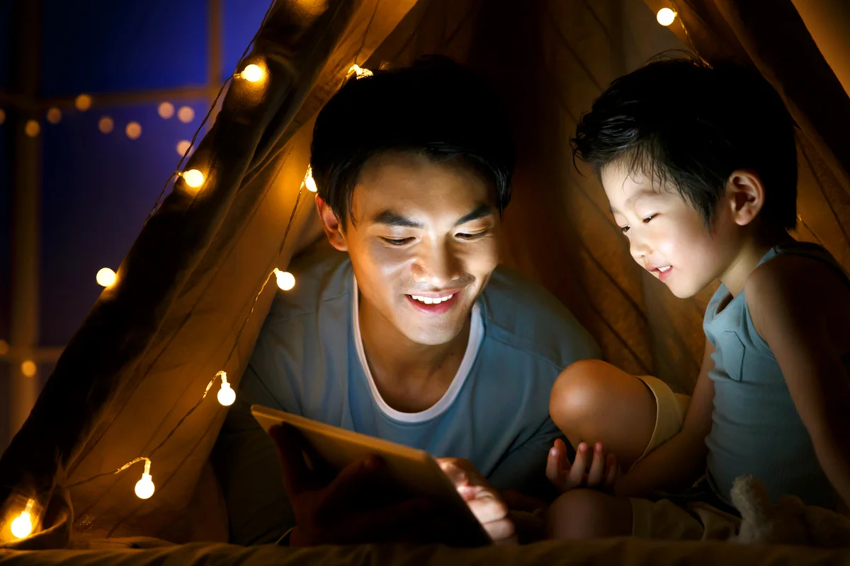 Father and son in a tent using tablet together