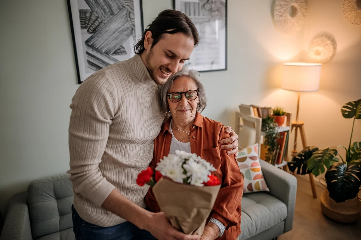 Son in visit to his mother, giving her flowers