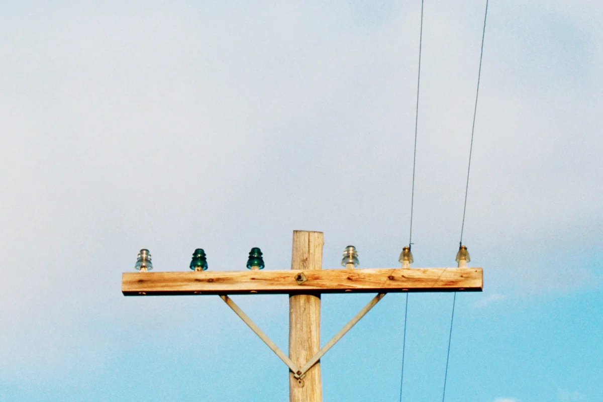 Old wooden telephone pole with glass insulators holds