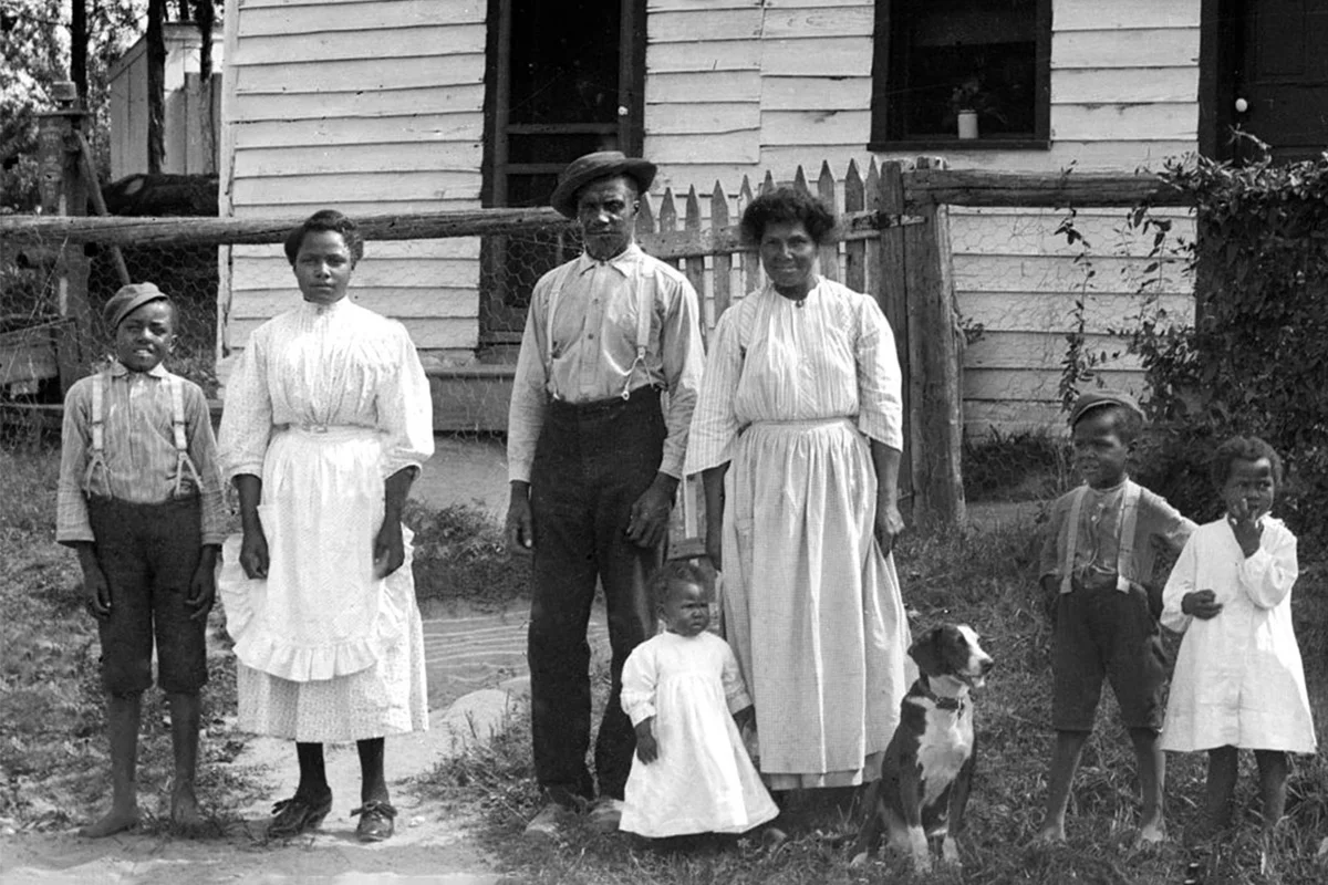 Black family stands in front of their home 1920s