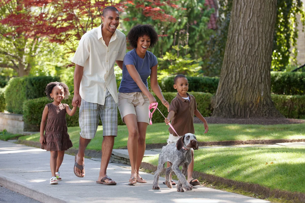 family exercising walking together outside with pet dog