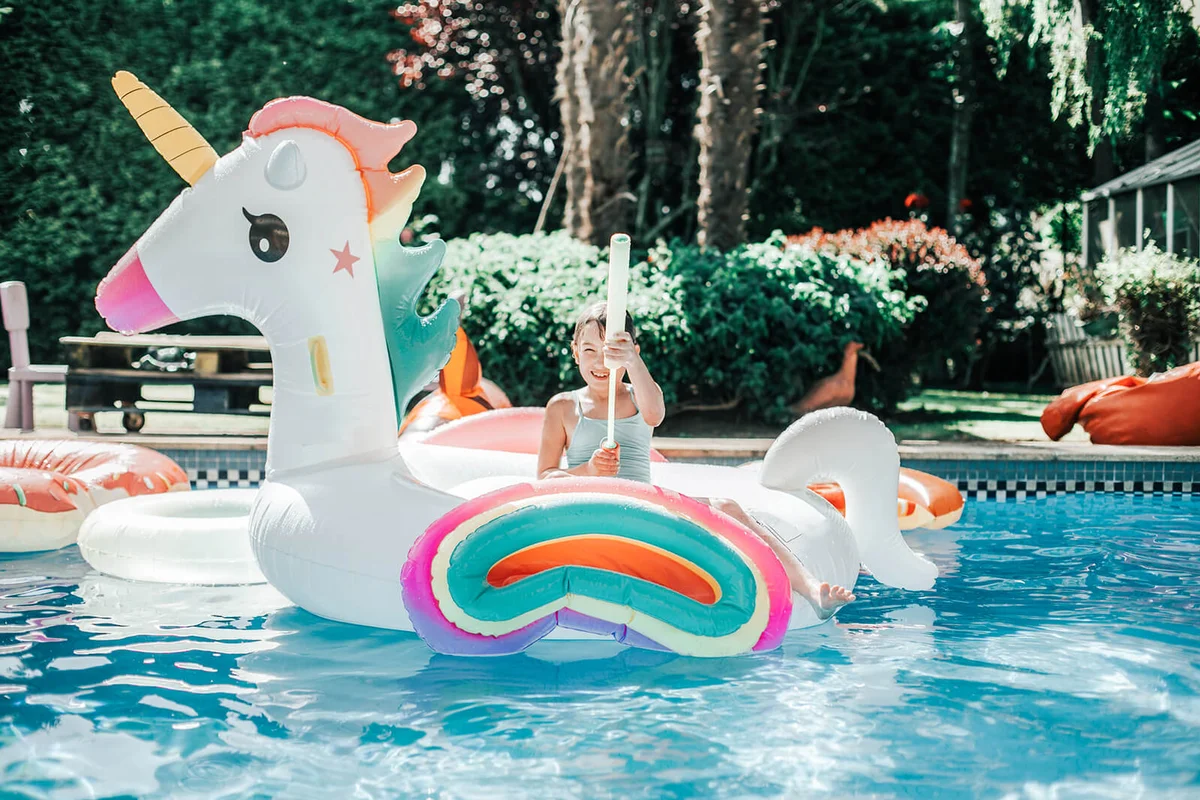 girl playing in a big unicorn inflatable ring at pool in summer