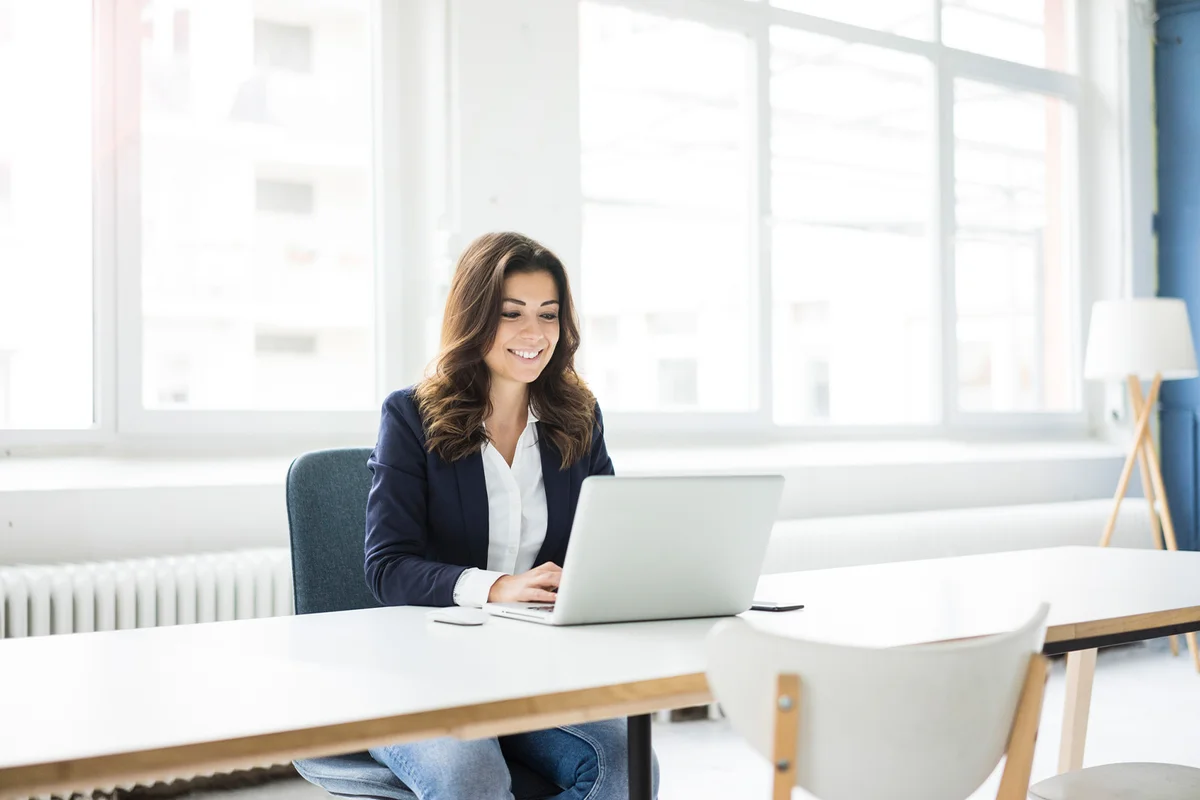 Businesswoman sitting at desk in the office working on laptop