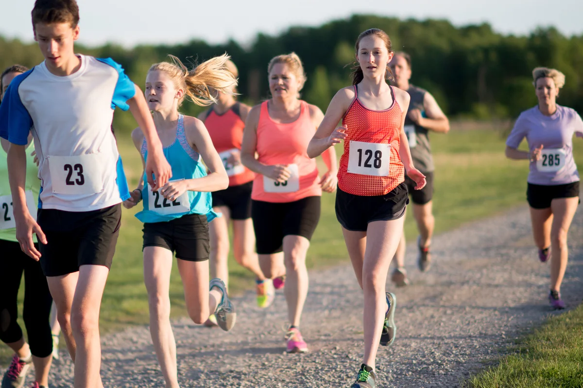 A multi-ethnic group of children and adults are running a race together