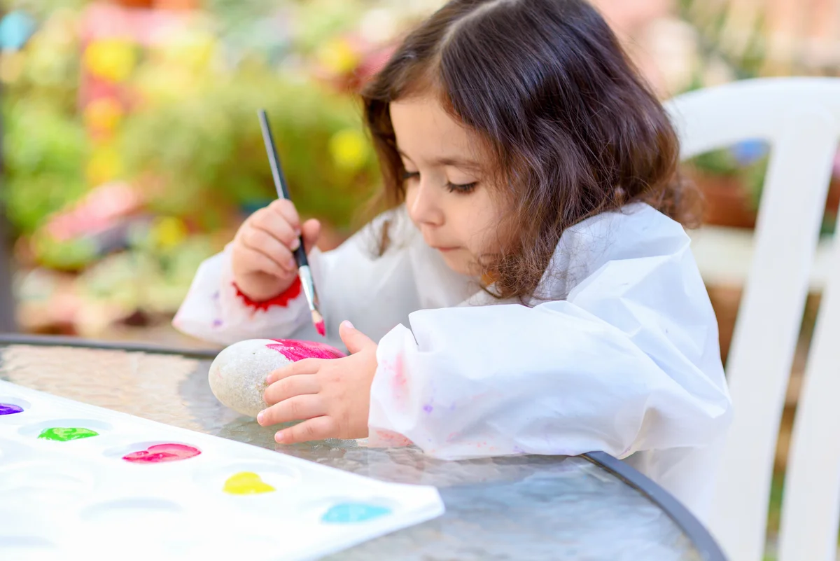 toddler girl painting a rock