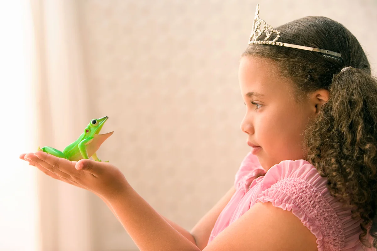 girl princess looking at toy frog in her hand