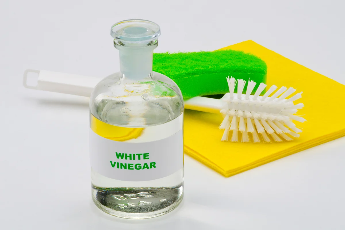 White vinegar in a glass bottle. White background. Organic cleaner.