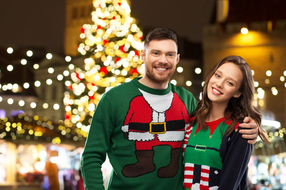 happy couple in ugly sweaters at christmas market