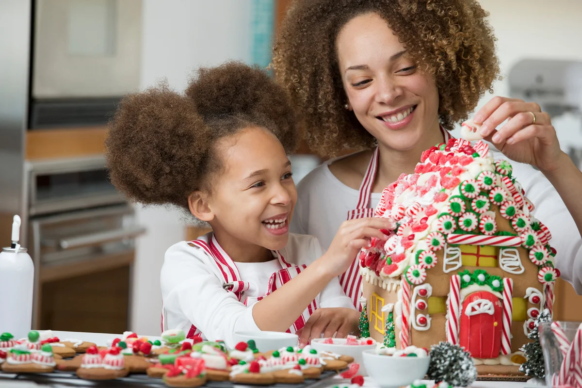 mother and daughter decorating gingerbread house