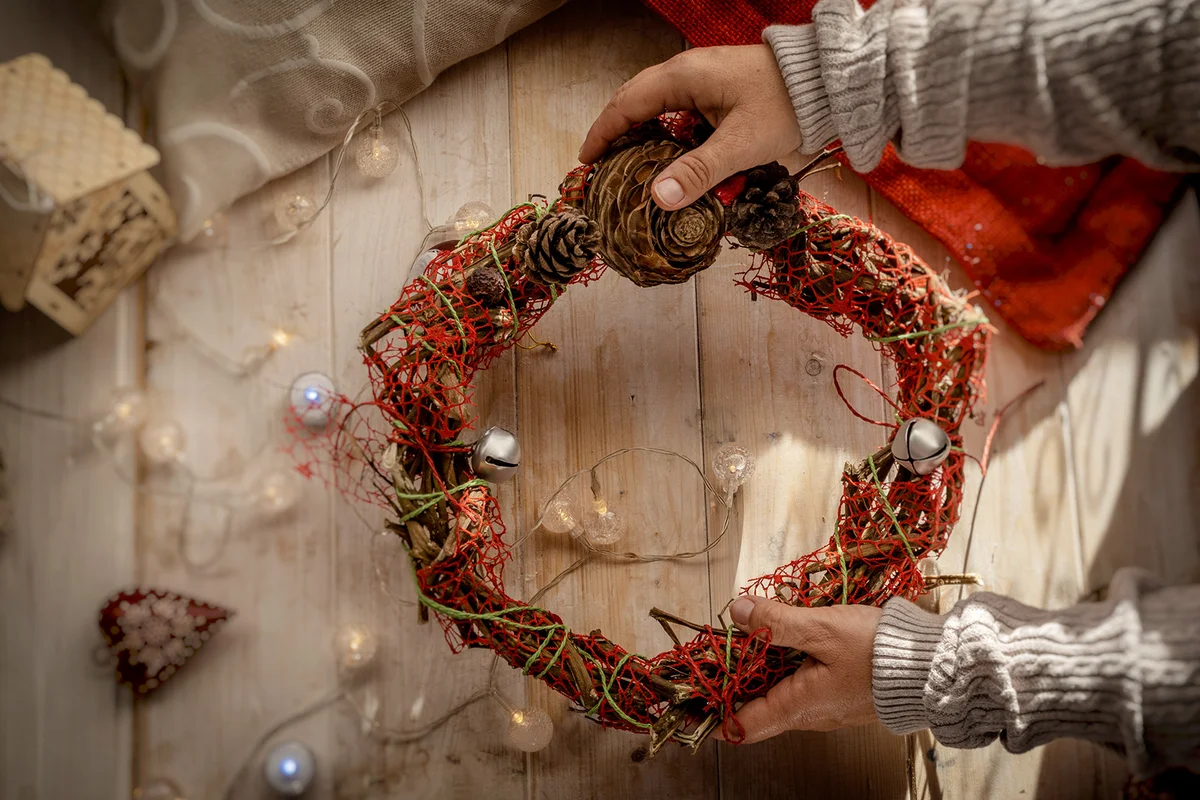 hands hold up a decorative christmas wreath