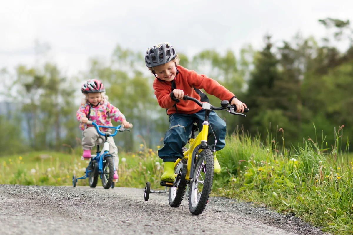 Little boy and his younger sister cycling outdoors