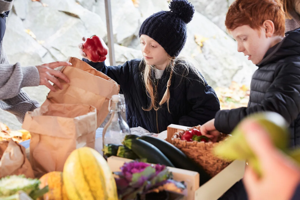 brother and sister buying vegetables at a fall farmers market