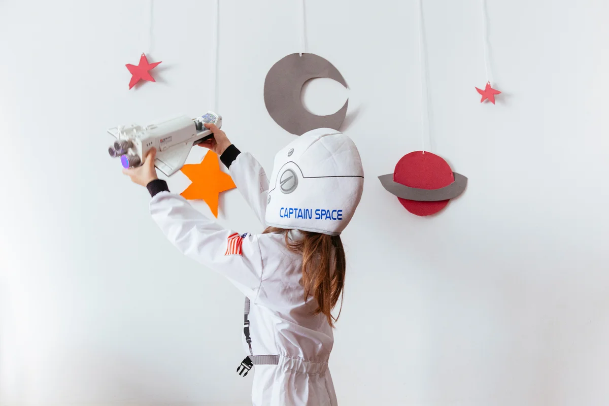 Girl Wearing Space Suit Playing With Rocket
