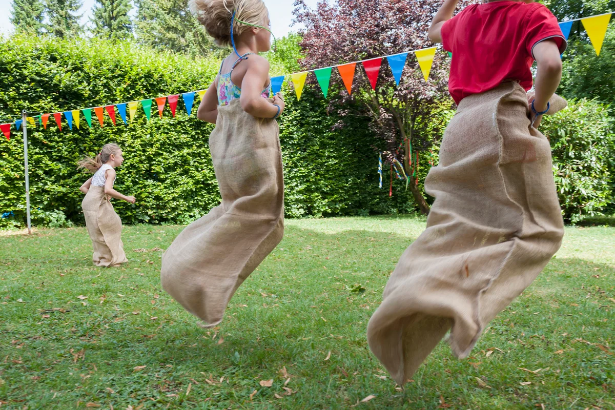Children having a sack race in garden on a birthday party