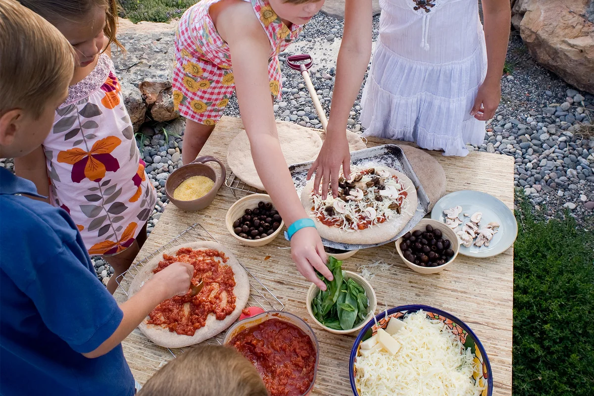 children making personal pizza at sleepover party