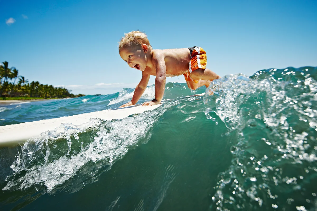 Toddler riding wave on surfboard