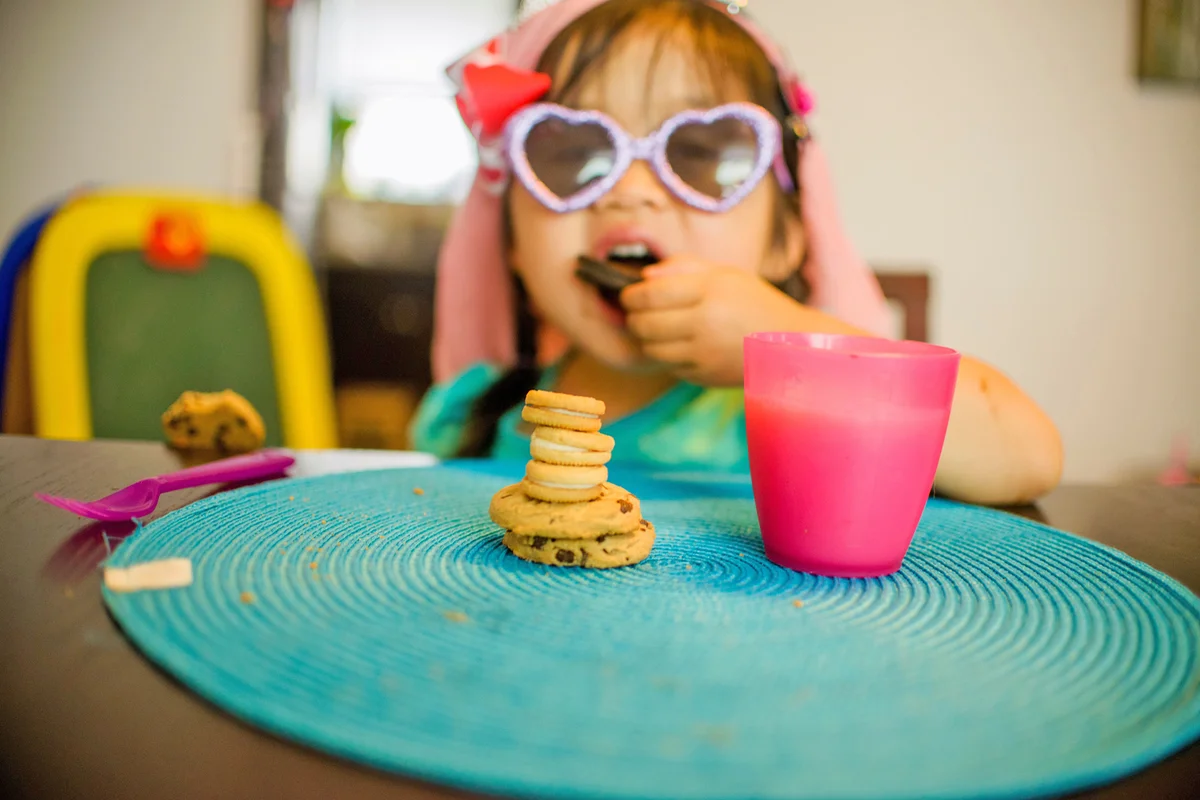Young girl sitting at table with drink and cookies