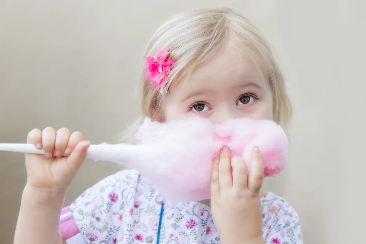 Young girl eating pink cotton candy