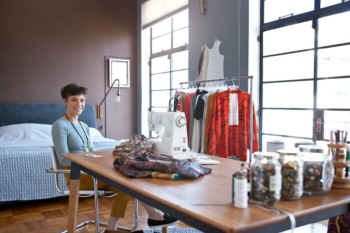 Female clothing designer sewing in her stylish apartment
