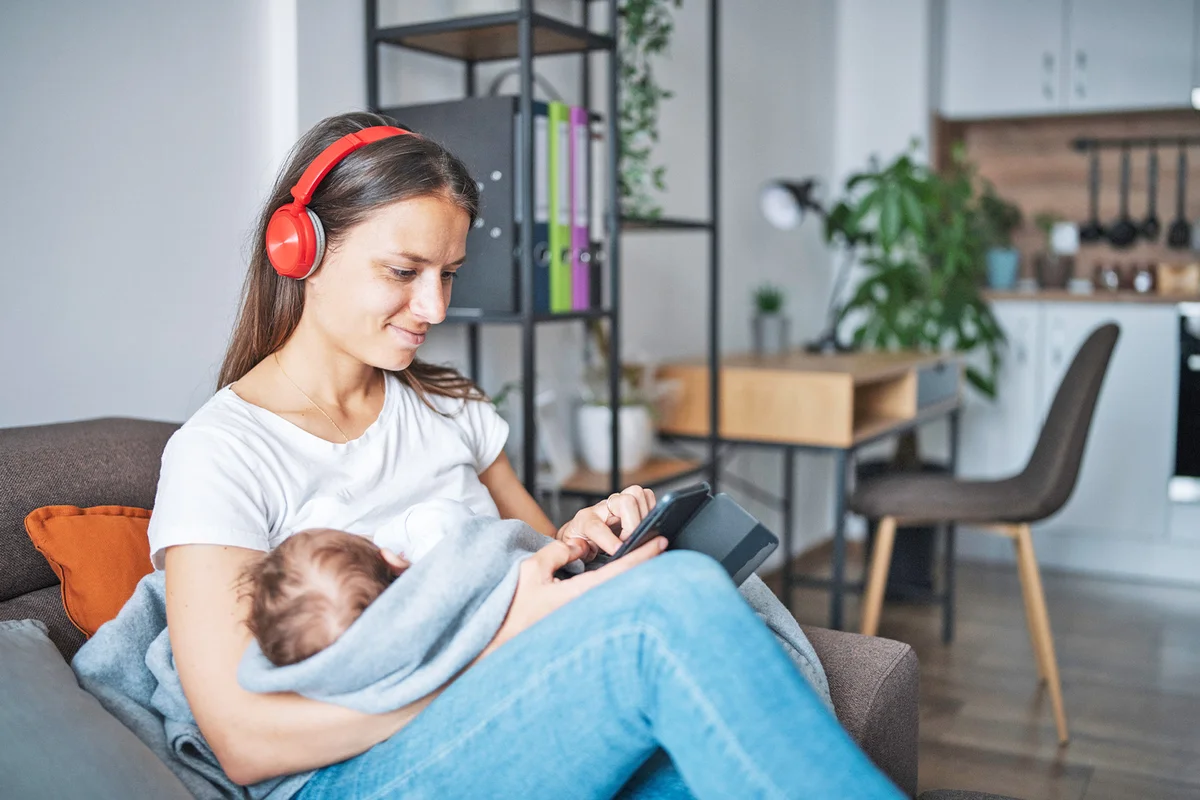 Young mother relaxing at home while holding her sleeping baby