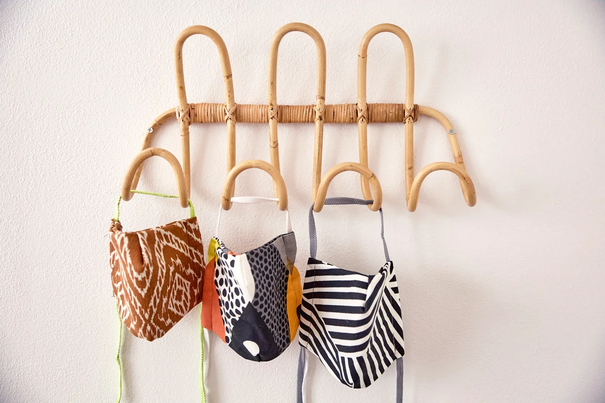 Three home made, hand sewn face masks sitting on a rattan rack