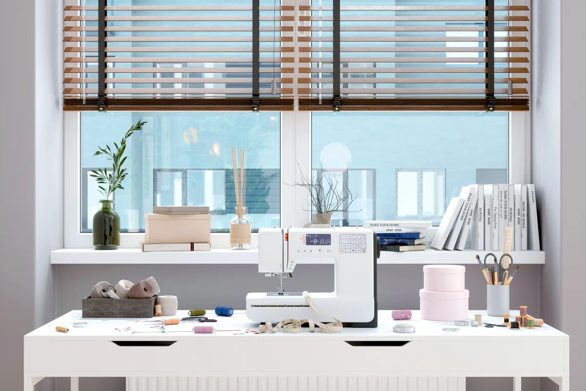 Sewing Machine And Other Sewing Equipments On The Table In Front Of Window