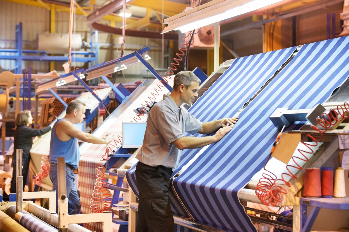 Textile workers inspecting striped woven thread in mill