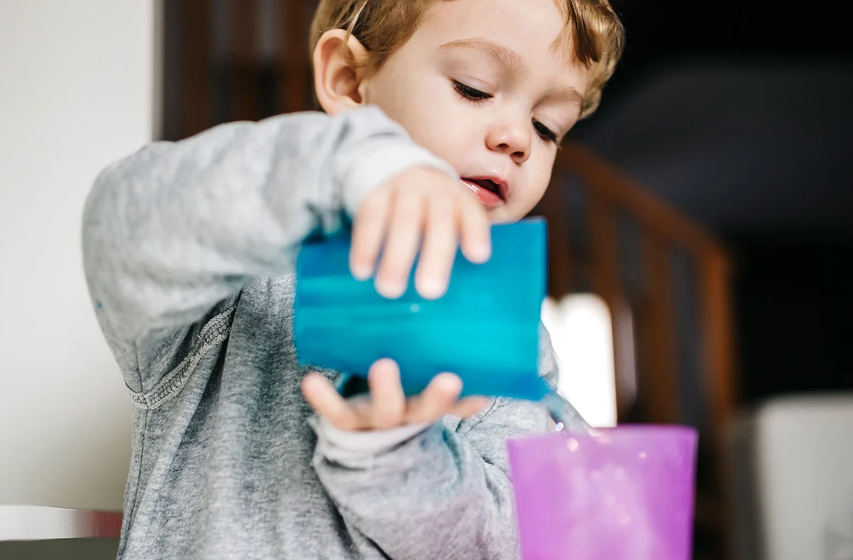toddler playing with cups of water