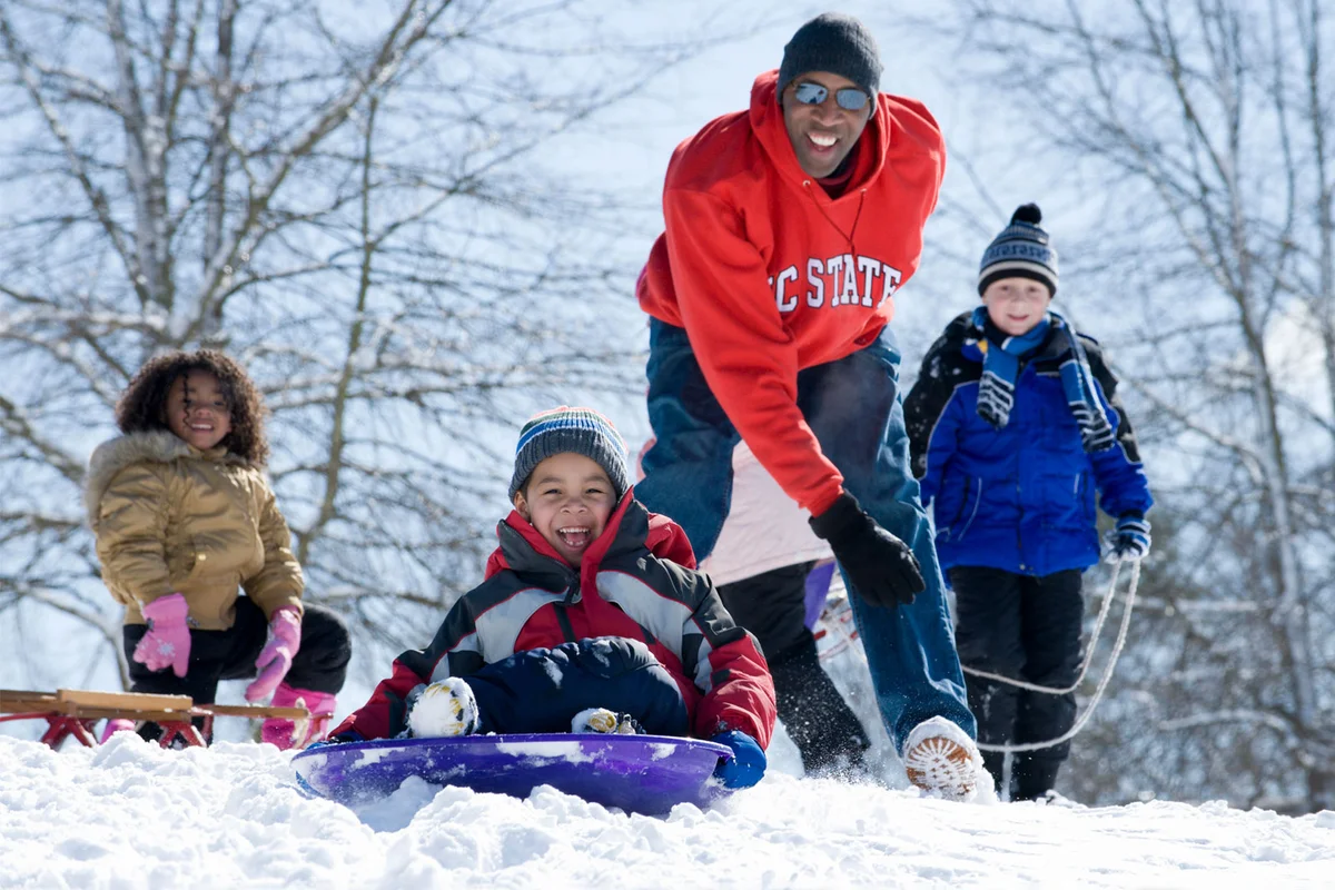 family snow sledding down hill