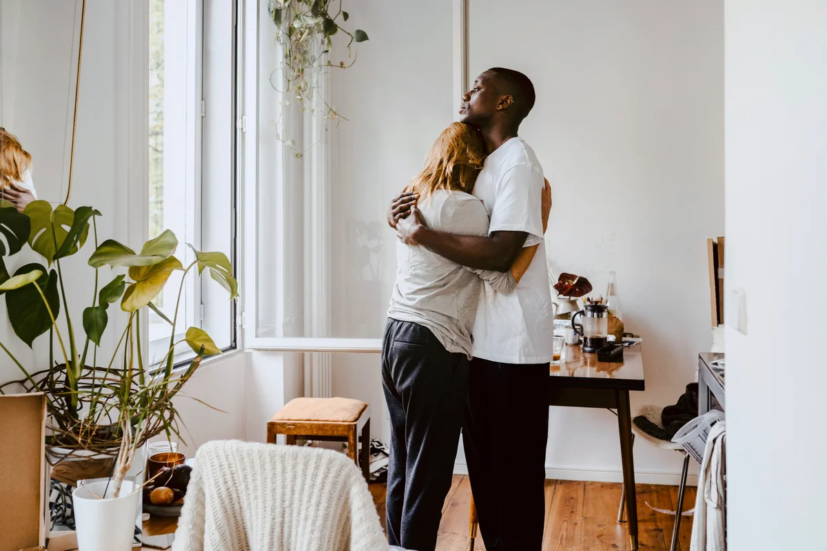 Mother embracing son while standing in living room at home