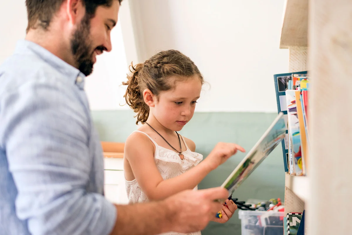 father and daughter with book in home library