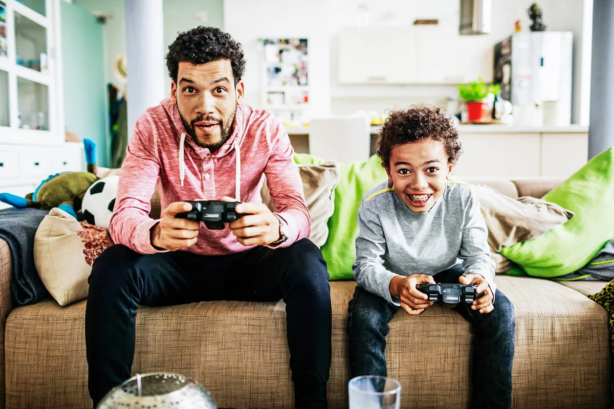 Father And Son Concentrating While Playing Video Games Together
