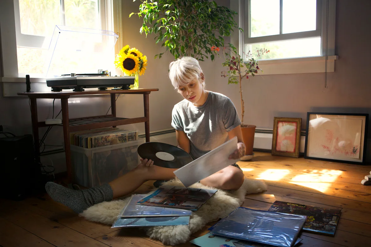Young woman looking at vinyl records while sitting on floor at home
