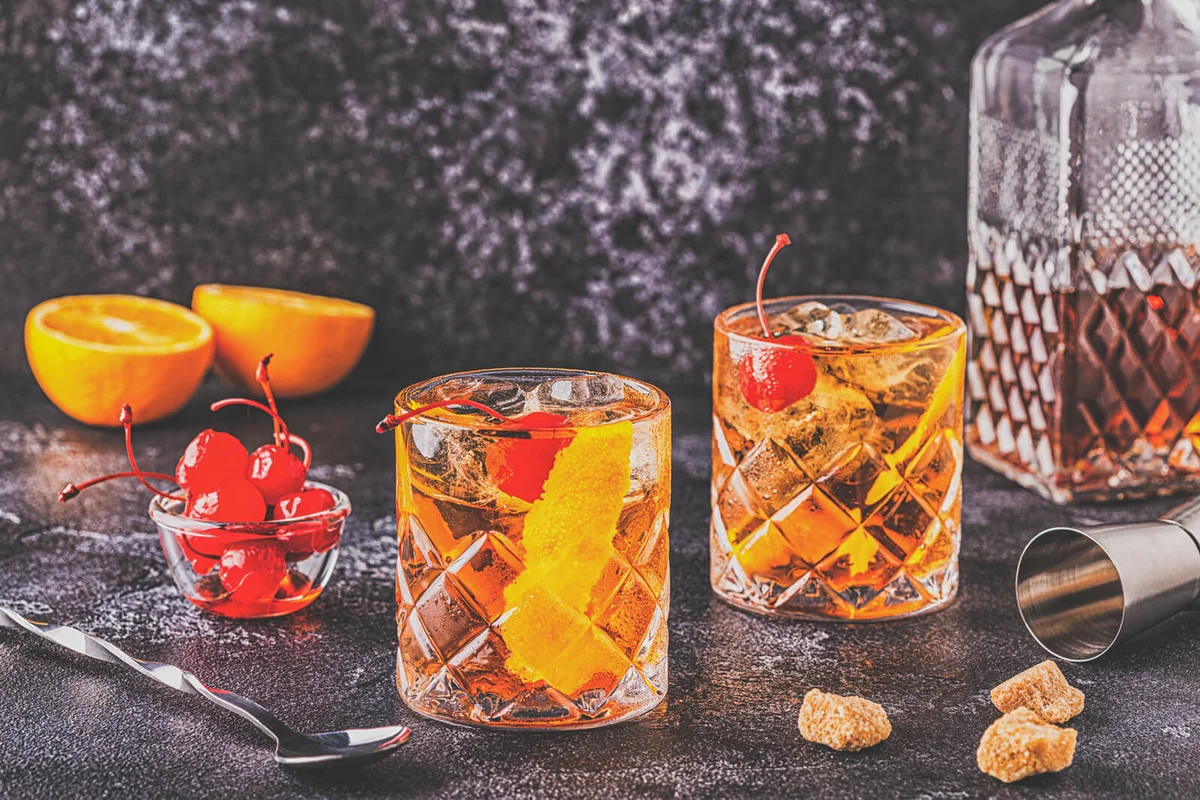 Old fashioned cocktail with cherries and orange twis