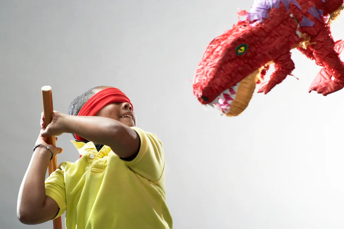 Boy preparing to hit dinosaur piñata