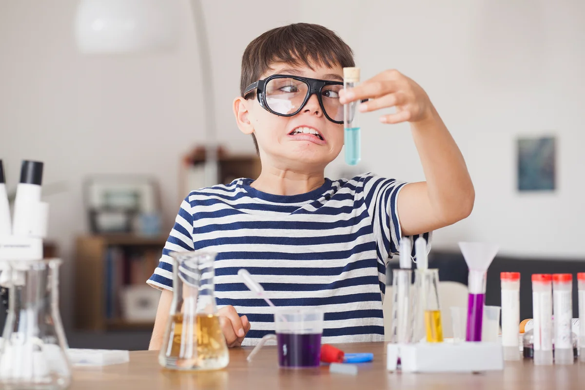 Cross eyed boy looking at test tube during science experiment in house